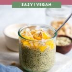 mango chia pudding topped with coconut in a glass with a spoon.
