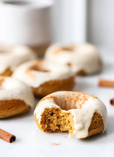 vegan baked pumpkin donuts with maple frosting on white marble
