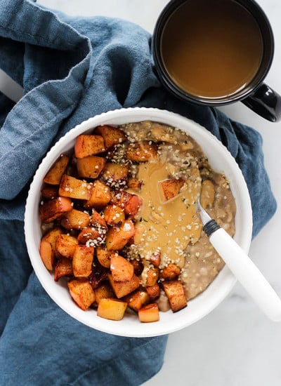 Bowl of oatmeal with sautéed cinnamon apples with blue napkin