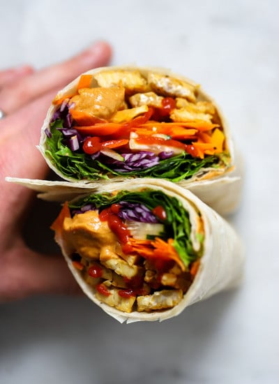 Tempeh wrap with peanut sauce held up with hand