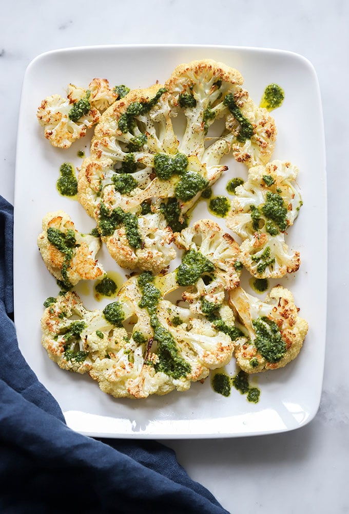 roasted cauliflower steak with pesto on white plate