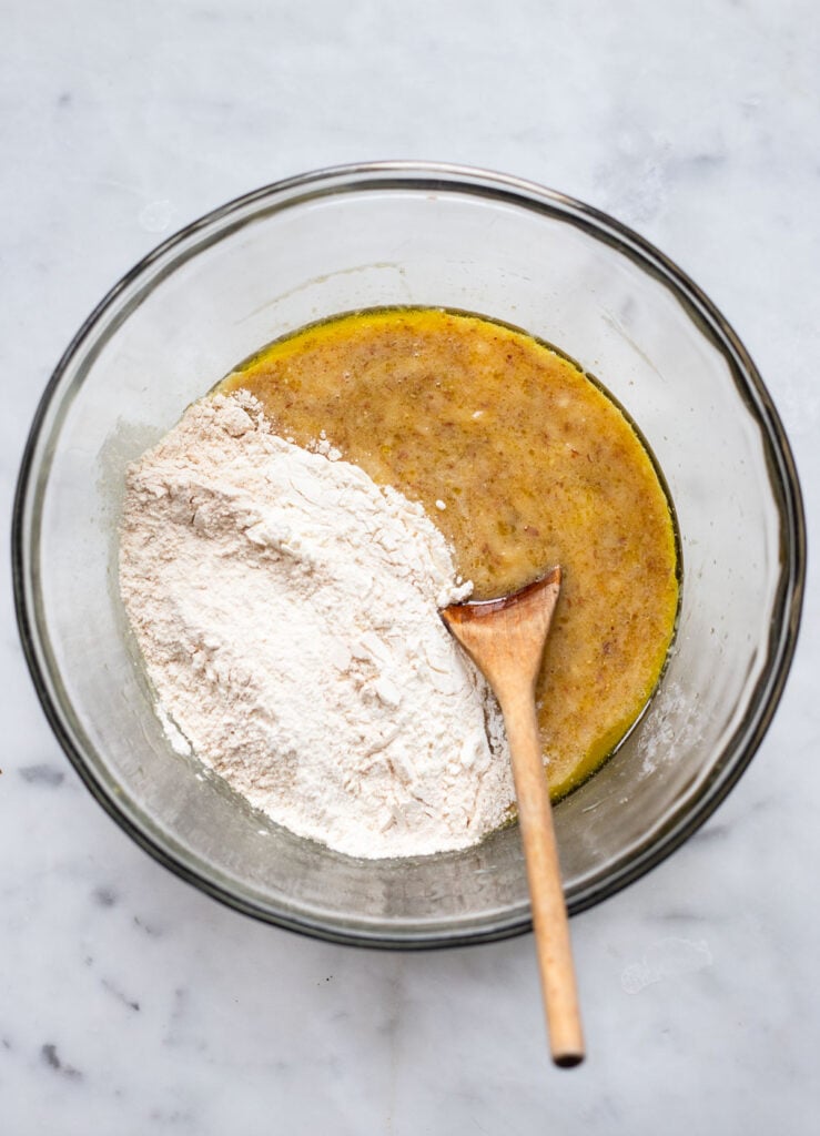 stir the dry ingredients (flour, baking powder, baking soda) into the wet ingredients (banana, oil, milk, vanilla, flax egg)