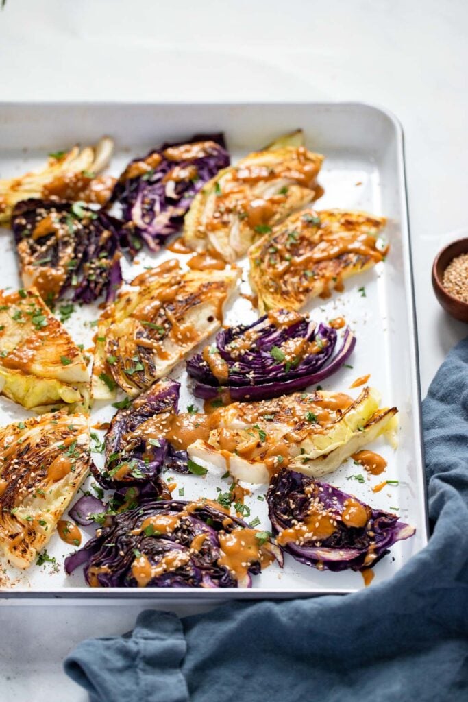 drizzle tahini sauce over roasted cabbage. garnish with sesame seeds and parsley.