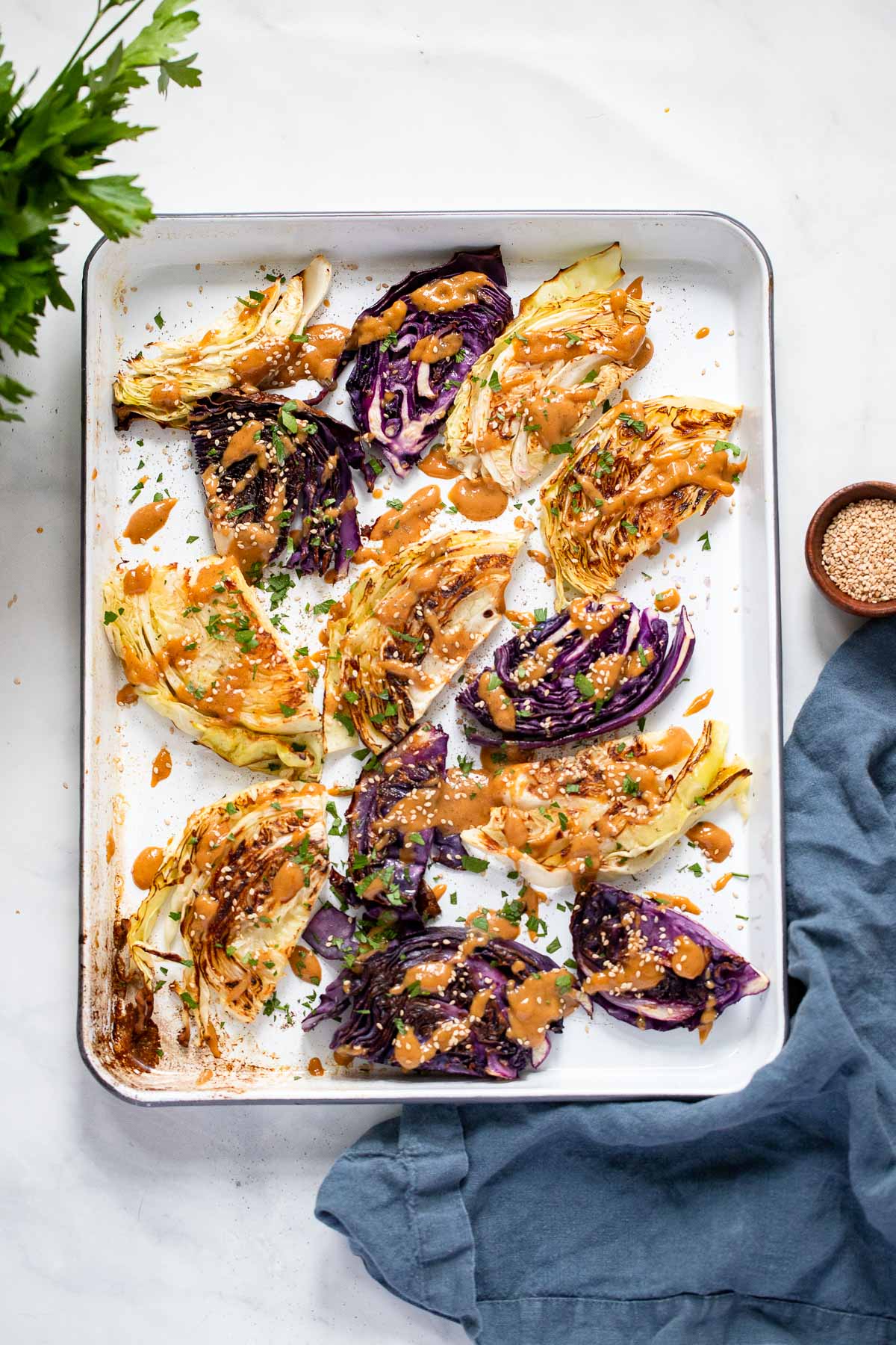roasted cabbage with tahini sauce on white baking sheet
