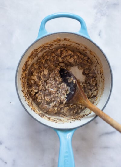 cooked chia spice oatmeal in small saucepan with wooden spoon. 