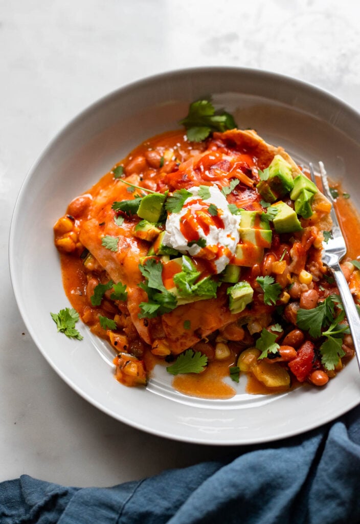 vegetarian slow cooker enchilada casserole topped with avocado, sour cream, and cilantro.
