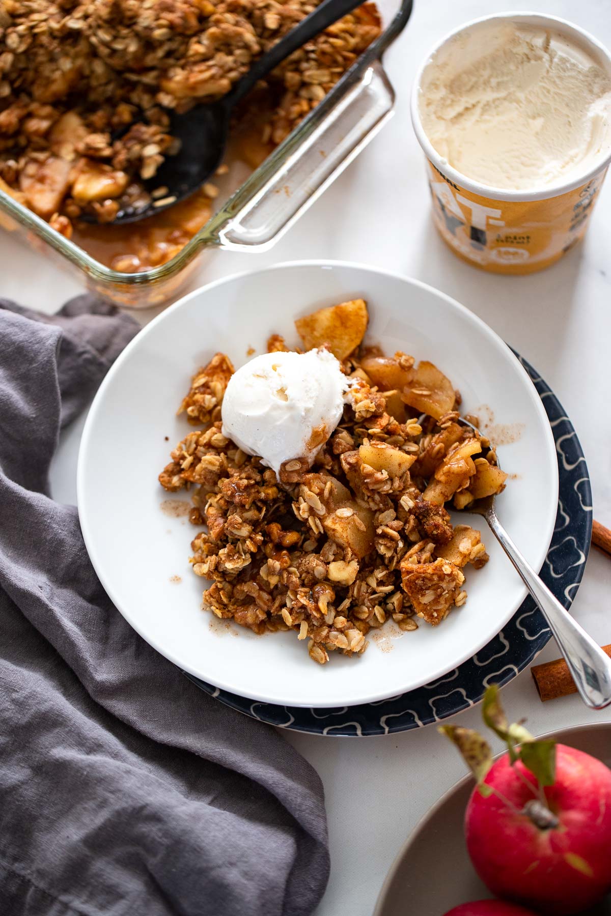 vegan apple crisp in bowl with vegan ice cream.