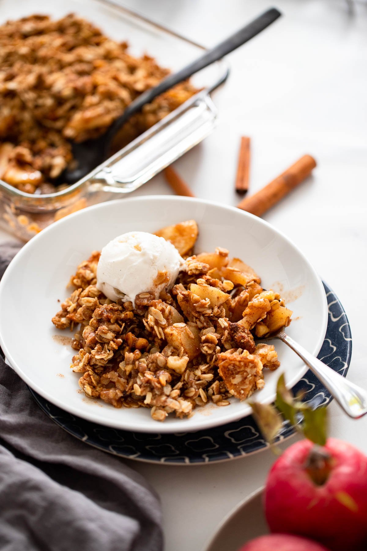 Vegan apple crisp in bowl with a scoop of vegan vanilla ice cream.