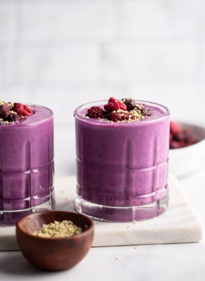 berry protein smoothie in glass garnished with berries.