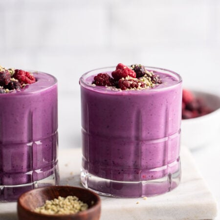 berry protein smoothie in glass garnished with berries.