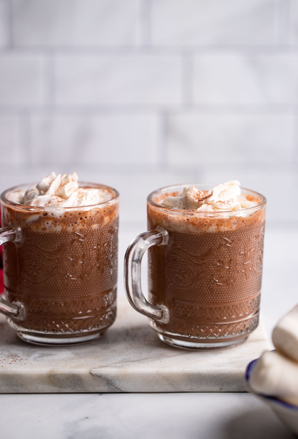 spiked vegan hot chocolates in glass mugs with whipped cream on top.