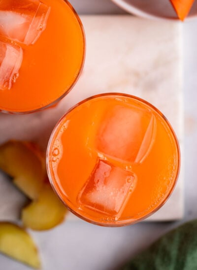 carrot ginger juice in glass with ice cubes. 