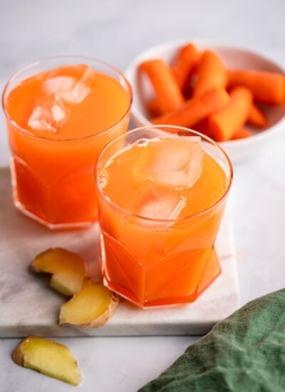 carrot ginger juice in glass with ice.