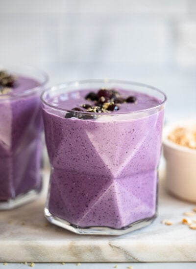 blueberry oat smoothie in glass garnished with blueberries.