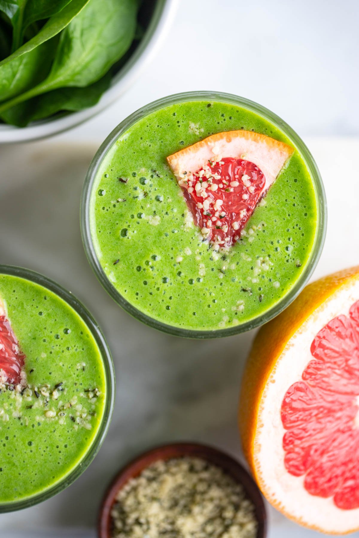 grapefruit green smoothie in glass with wedge of grapefruit and hemp hearts for garnish.