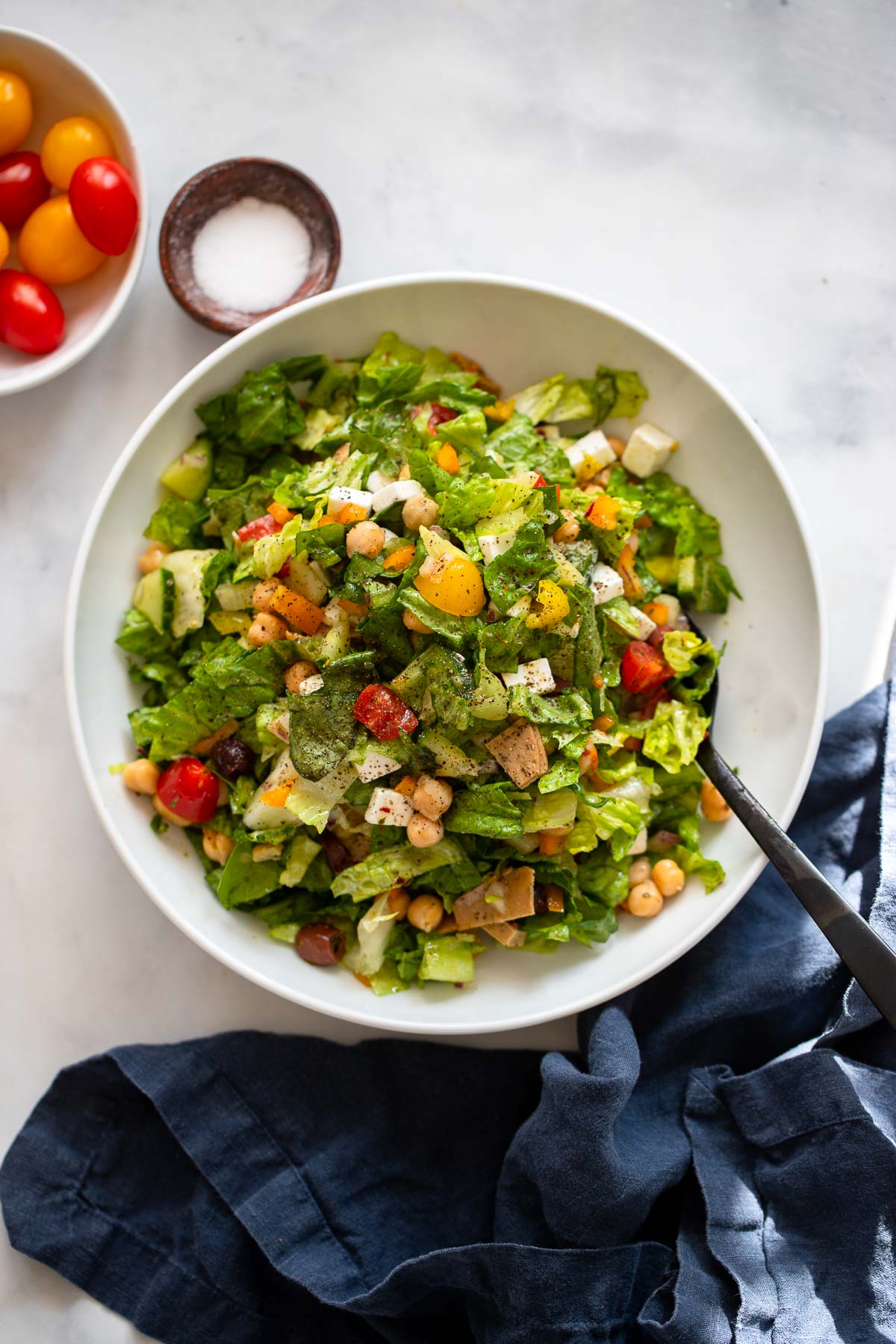 chopped Italian salad piled high in a bowl with a serving spoon.