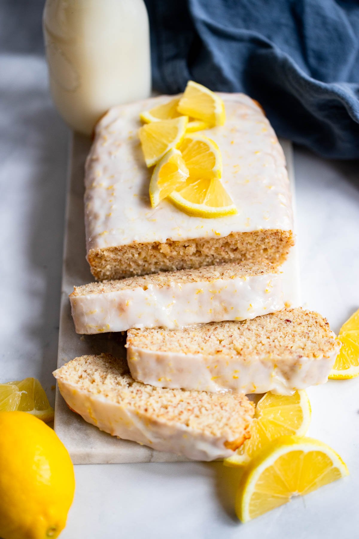 sliced vegan lemon loaf cake garnished with fresh lemon.