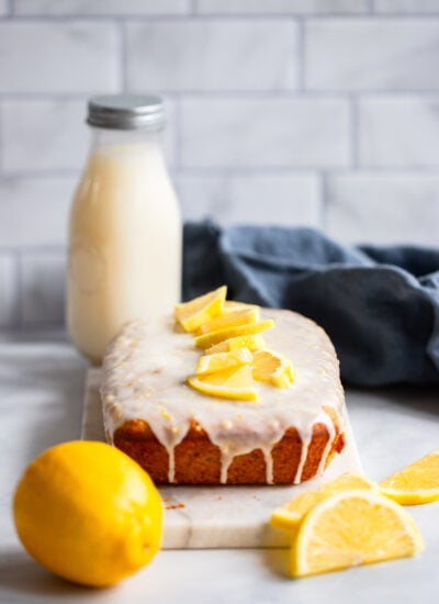 vegan lemon loaf on marble slab with fresh lemon slices.