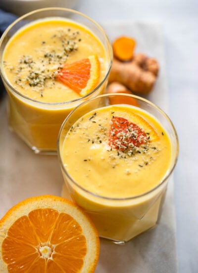mango turmeric smoothie in glass garnished with hemp hearts.