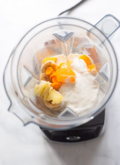 mango turmeric smoothie ingredients in blender pitcher before blending. 