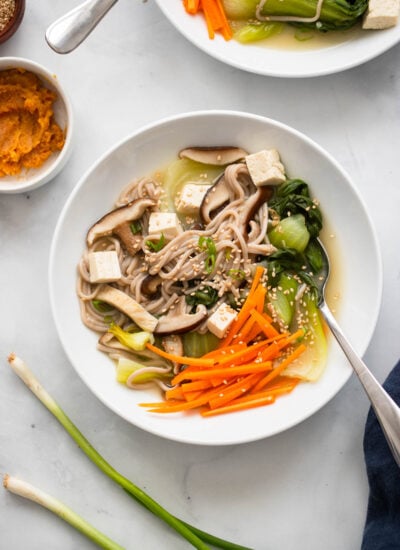 miso soba noodle soup garnished with sesame seeds in a white bowl.
