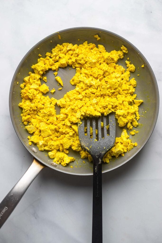tofu scramble in a non-stick skillet with a spatula. 
