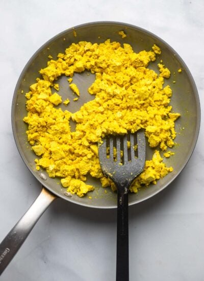 scrambled tofu in a non stick skillet with a spatula.
