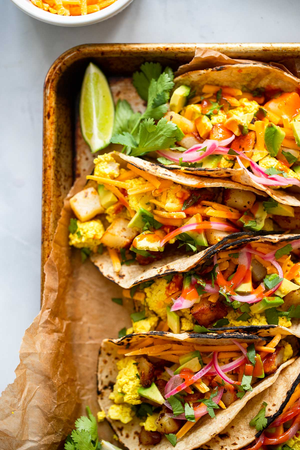 vegan breakfast tacos garnished with avocado and cilantro on a tray.