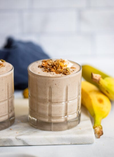 tahini date smoothie in a glass with granola on top.