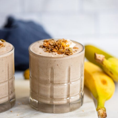 tahini date smoothie in a glass with granola on top.