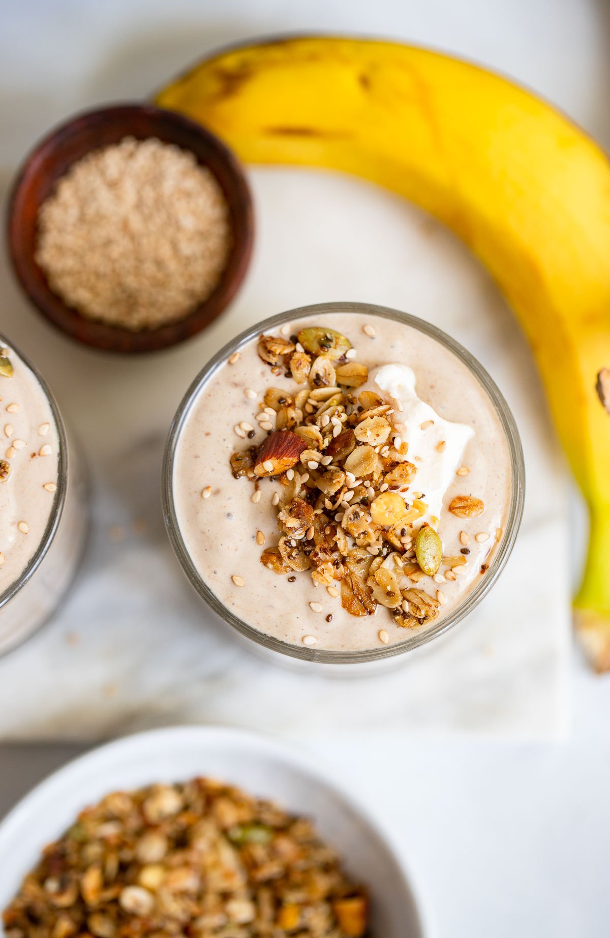 tahini smoothie in glass topped with granola and yogurt.