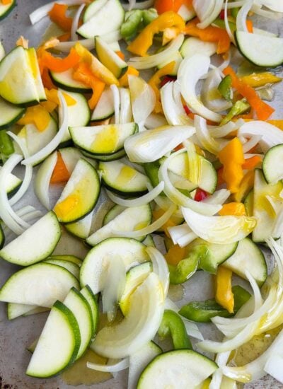mixed vegetables with oil and spices on a baking sheet. 