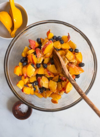 crisp fruit filling mixed together in a large mixing bowl with a wooden spoon. 