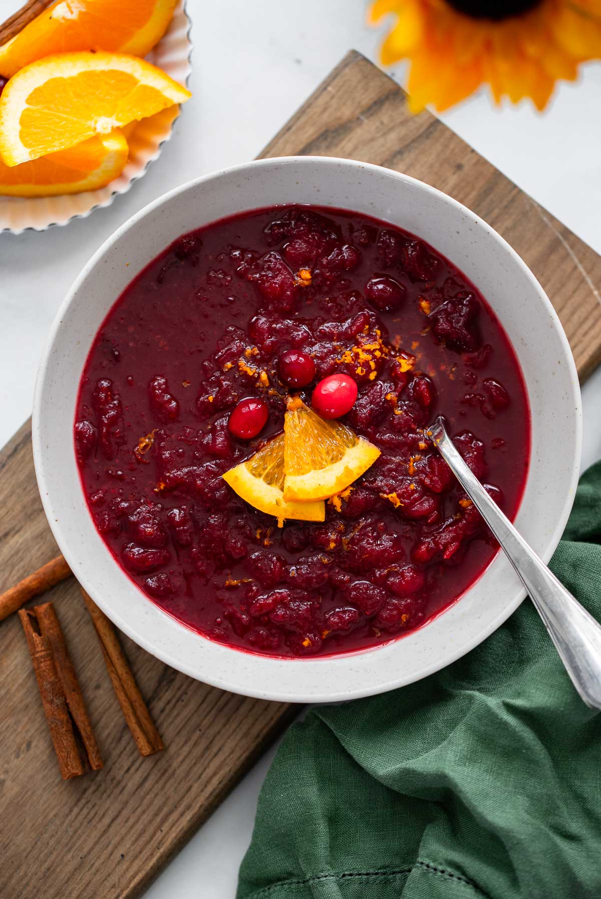cranberry sauce in a gray serving bowl garnished with fresh orange wedges. 