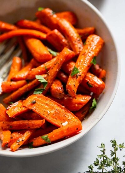 roasted carrots with thyme in a white serving bowl.