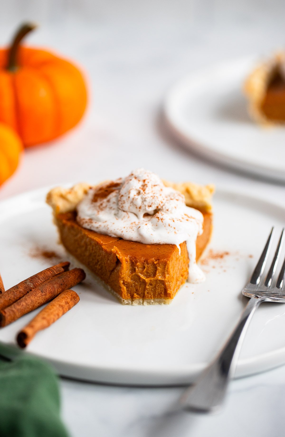 close up of a slice of vegan pumpkin pie topped with whipped cream with bite taken out of it.