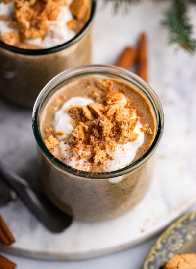 gingerbread overnight oats in a glass topped with crumbled cookies.