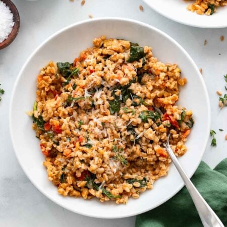 farro risotto in a white bowl garnished with parmesan.