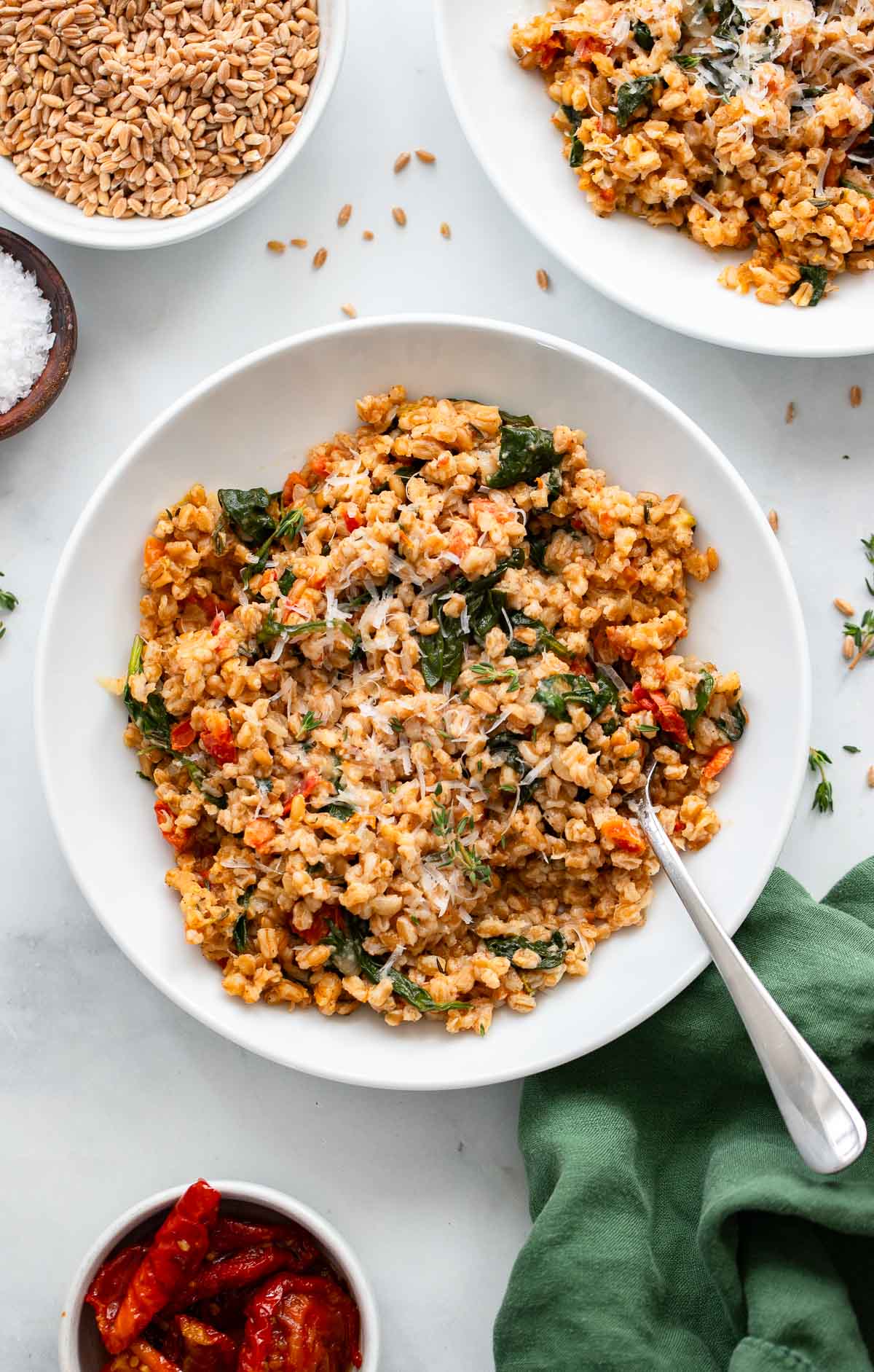 easy farro risotto in a white bowl garnished with shredded parmesan.