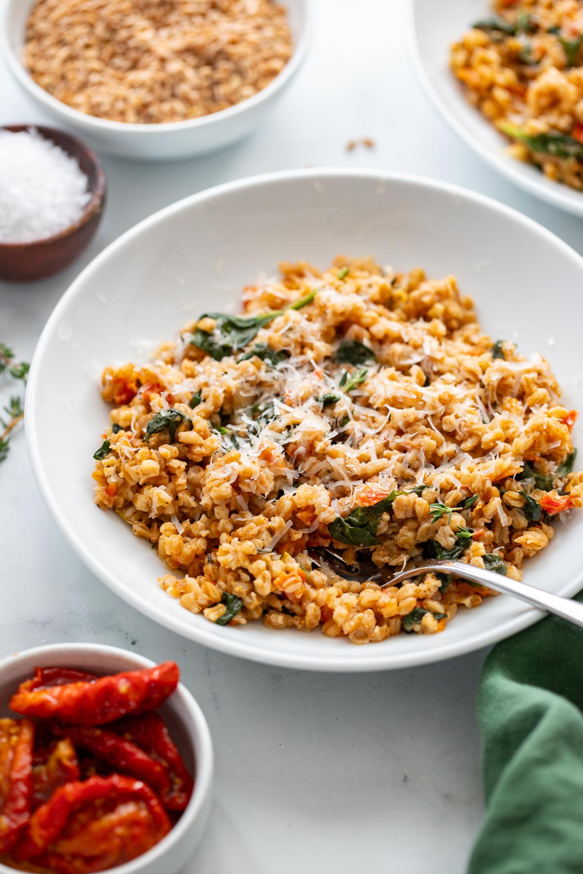 farro risotto garnished with shredded parmesan in a white bowl. 