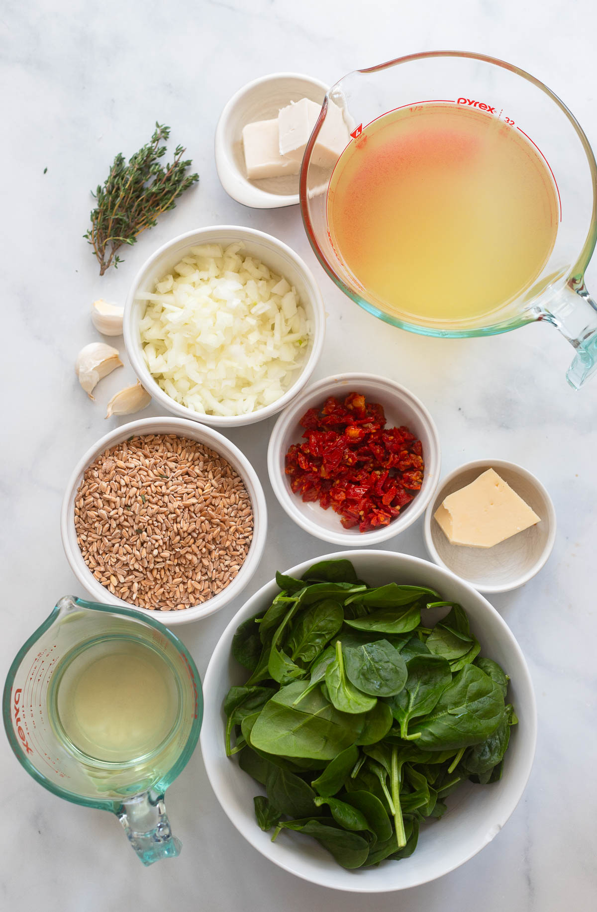 farro risotto ingredients in small bowls on a white background. 