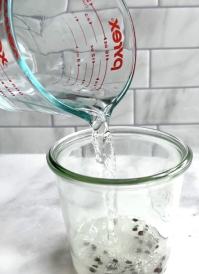 hot water pouring into a jar with black pepper. 