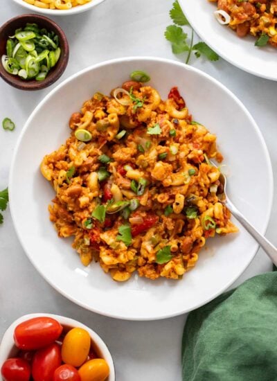vegan chili mac in a white bowl garnished with green onions.