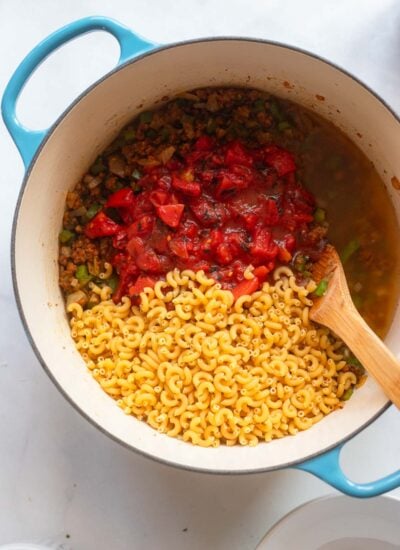 cooked vegan ground meat in a dutch oven topped with tomatoes and macaroni. 