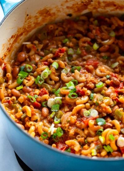 cooked chili Mac in a dutch oven garnished with green onion.
