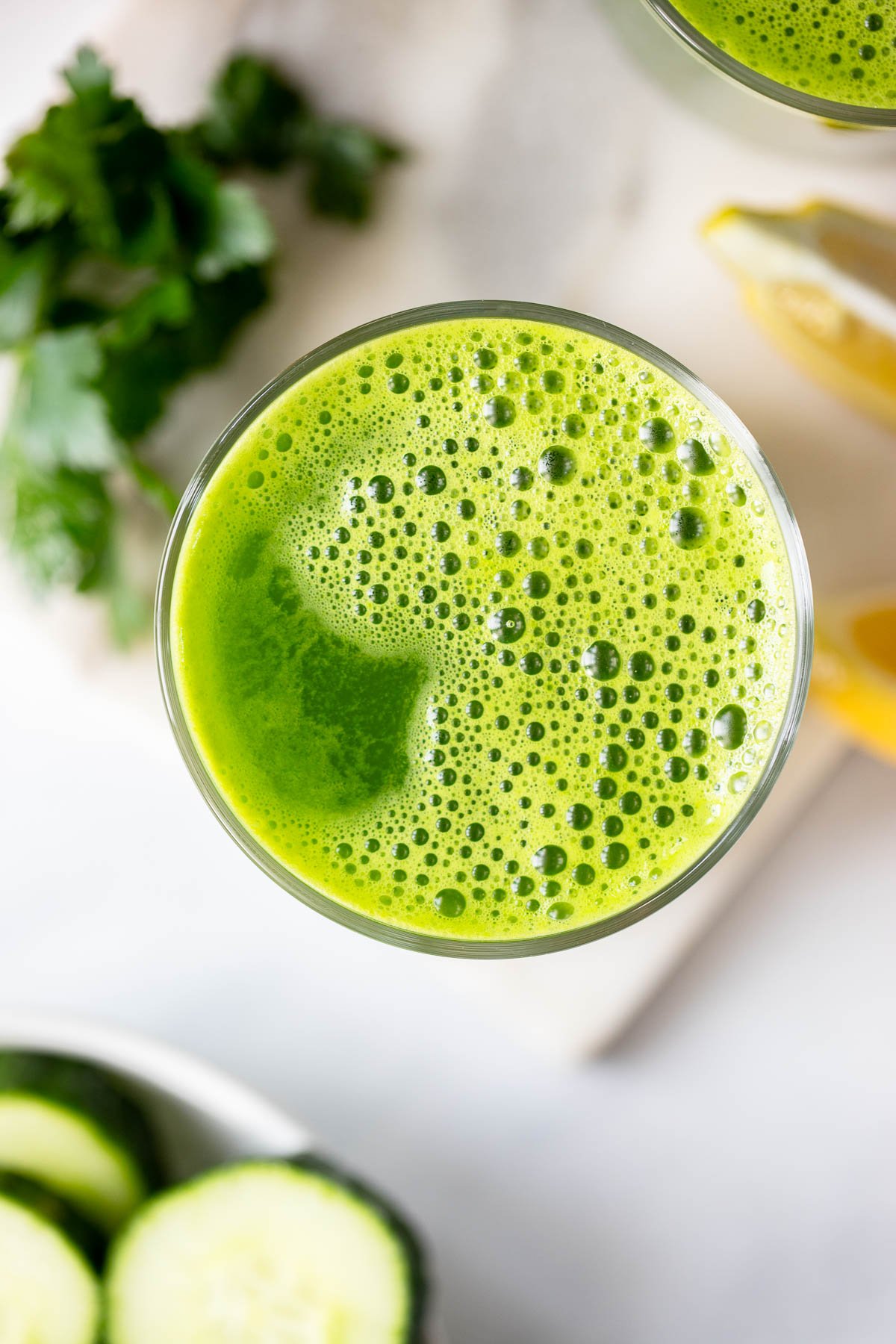 blender green juice in a glass closeup to see bubbles. 