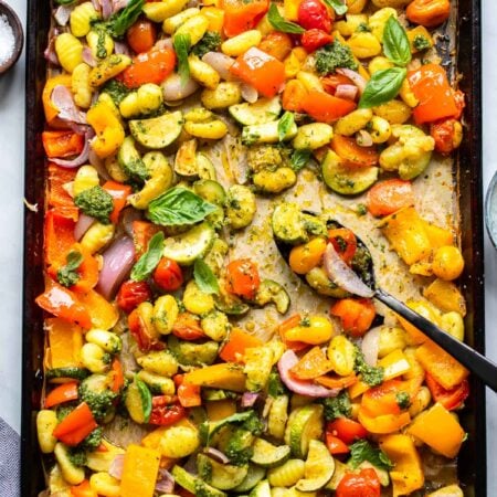 sheet pan gnocchi with pesto with a serving spoon.