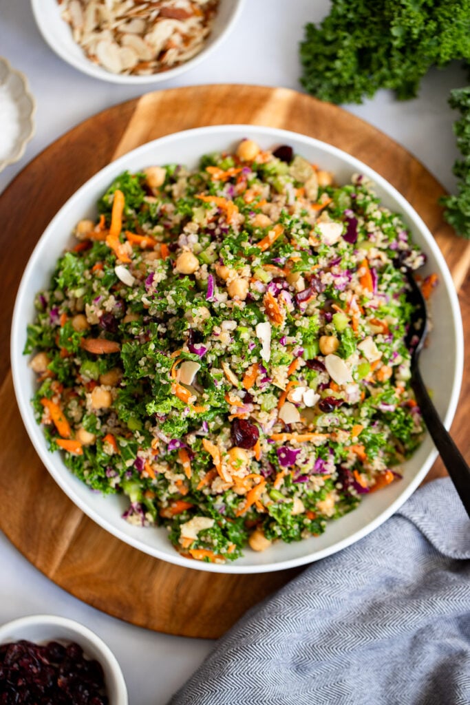 quinoa and celery salad in a large white bowl with a serving spoon. 