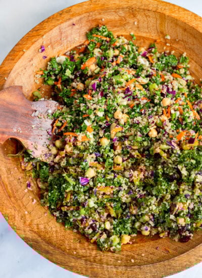 tossed celery and quinoa salad in a large wooden bowl with a serving utensil. 